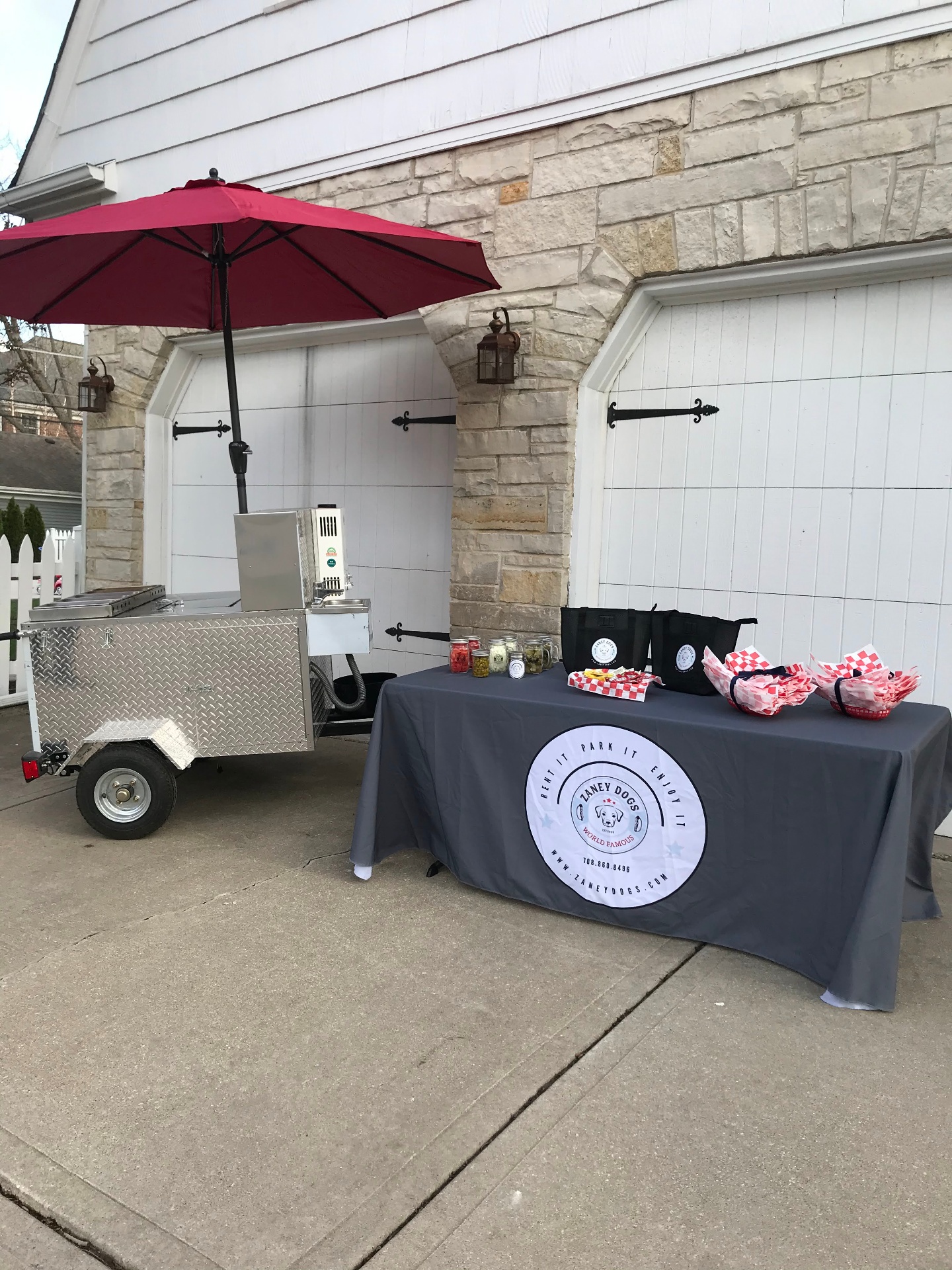 The full Zaney Dogs hot dog cart setup with red umbrella