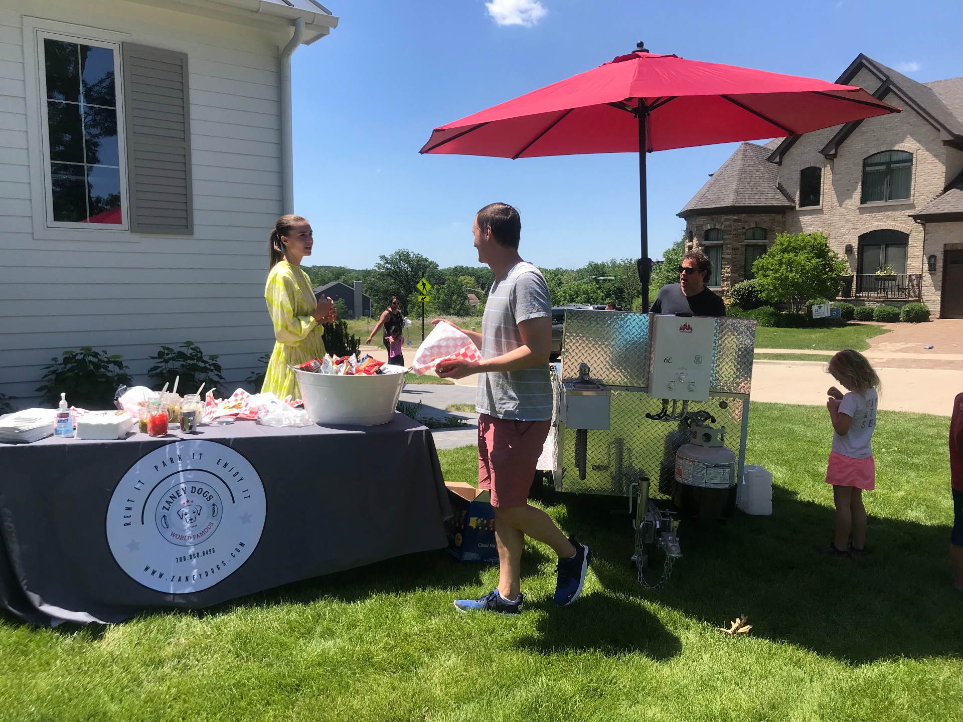Guests enjoying a backyard party with the Zaney Dogs cart